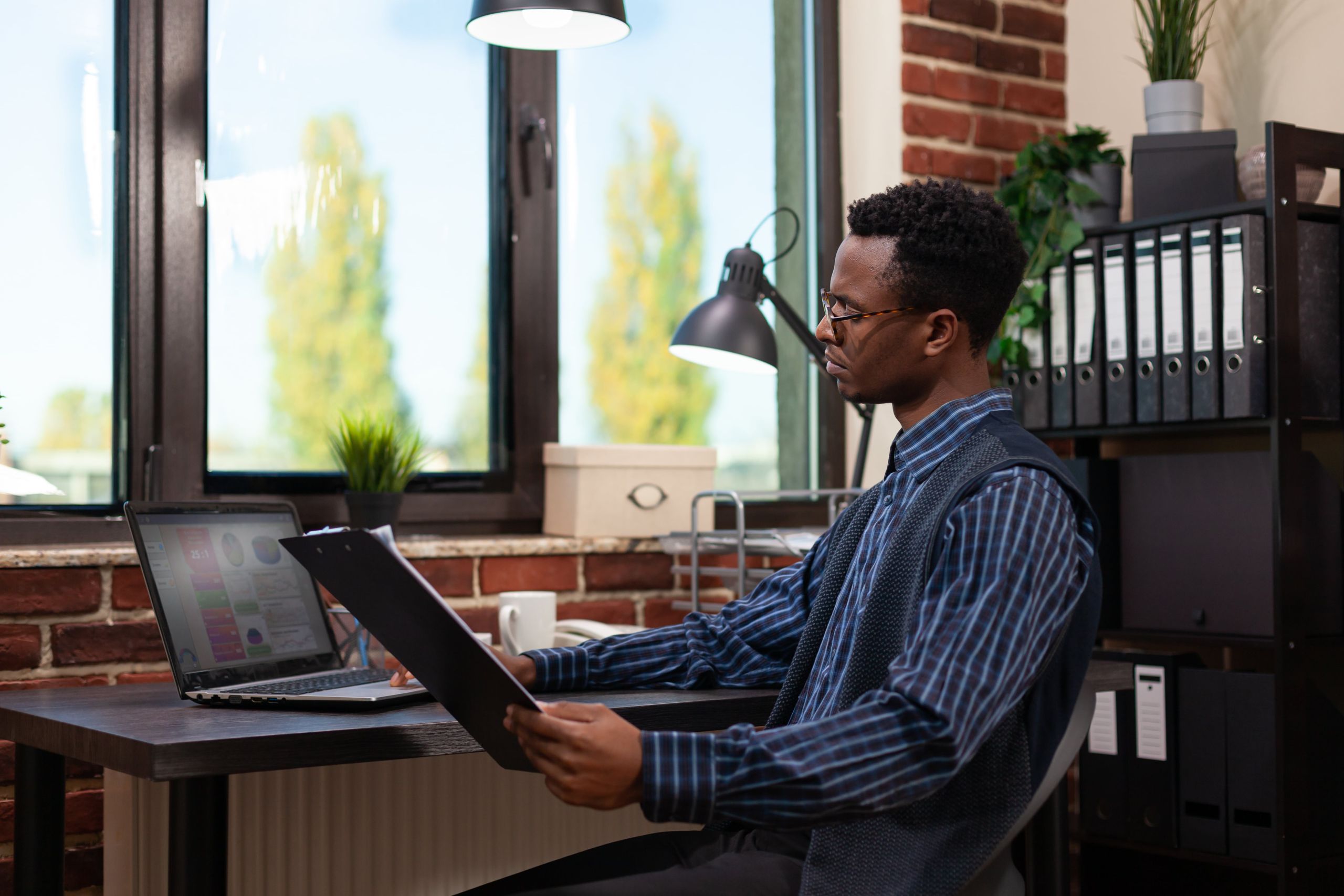 Empreendedor Olhando Para A Tela Do Laptop Com Resultados De Vendas Segurando Uma Prancheta Com Graficos De Negocios Min - Auster Inteligência Contábil