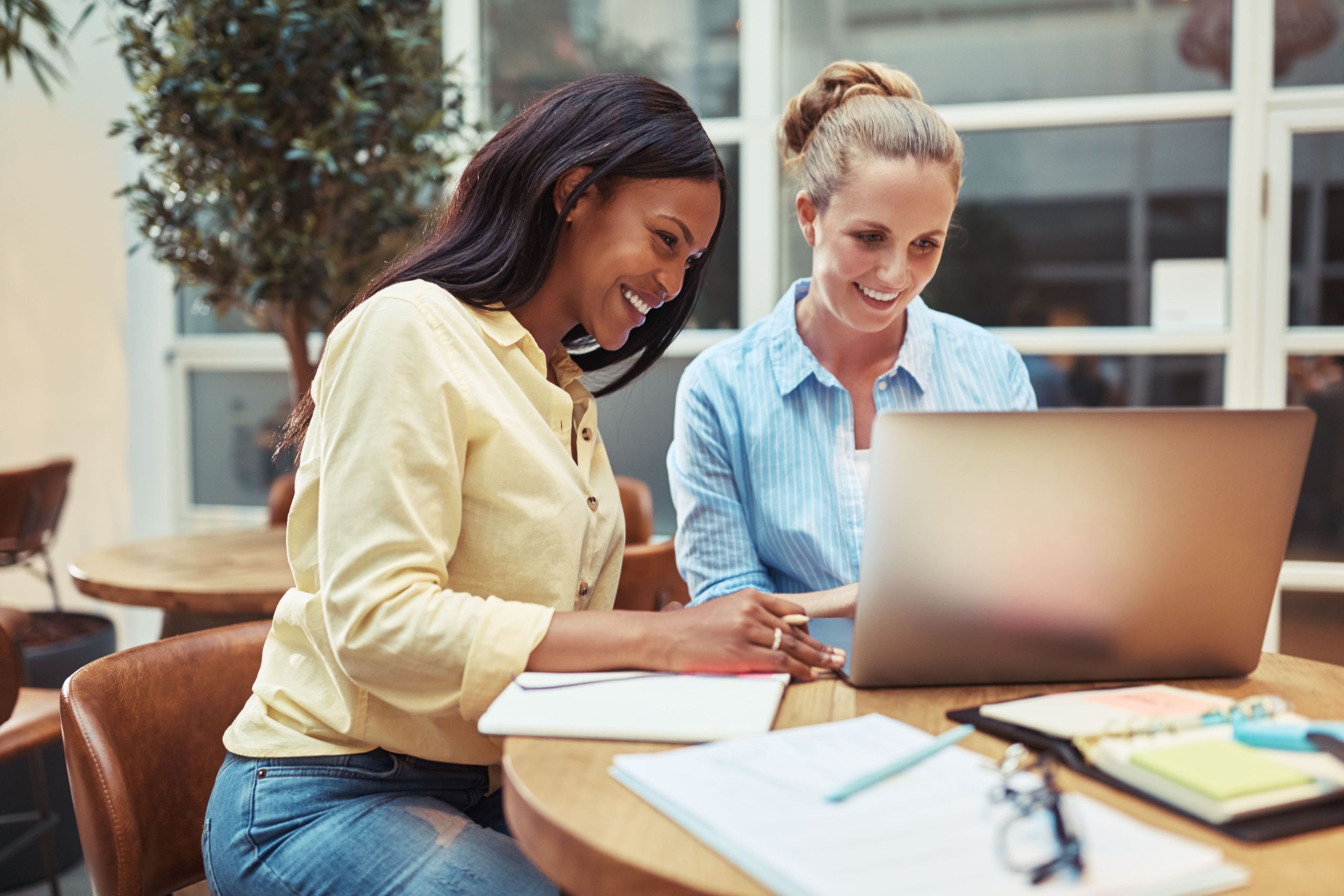 Rindo Jovens Mulheres De Negocios Usando Um Laptop Em Uma Sala De Escritorio Min - Auster Inteligência Contábil