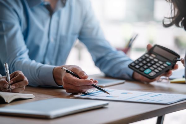 Businessman Pointing Graph And Using Calculator During A Business Meeting. - Auster Inteligência Contábil