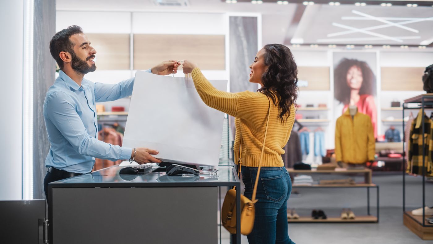 Clothing Store: Young Woman At Counter Buys Clothes. Friendly Re - Auster Inteligência Contábil