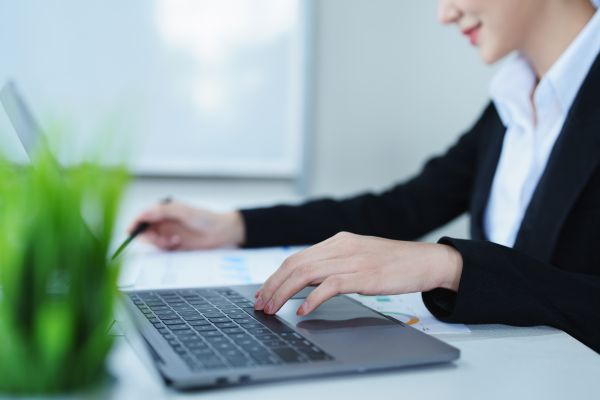 Portrait Of A Thoughtful Asian Businesswoman Looking At Financial Statements And Making Marketing Plans Using A Computer On Her Desk - Auster Inteligência Contábil
